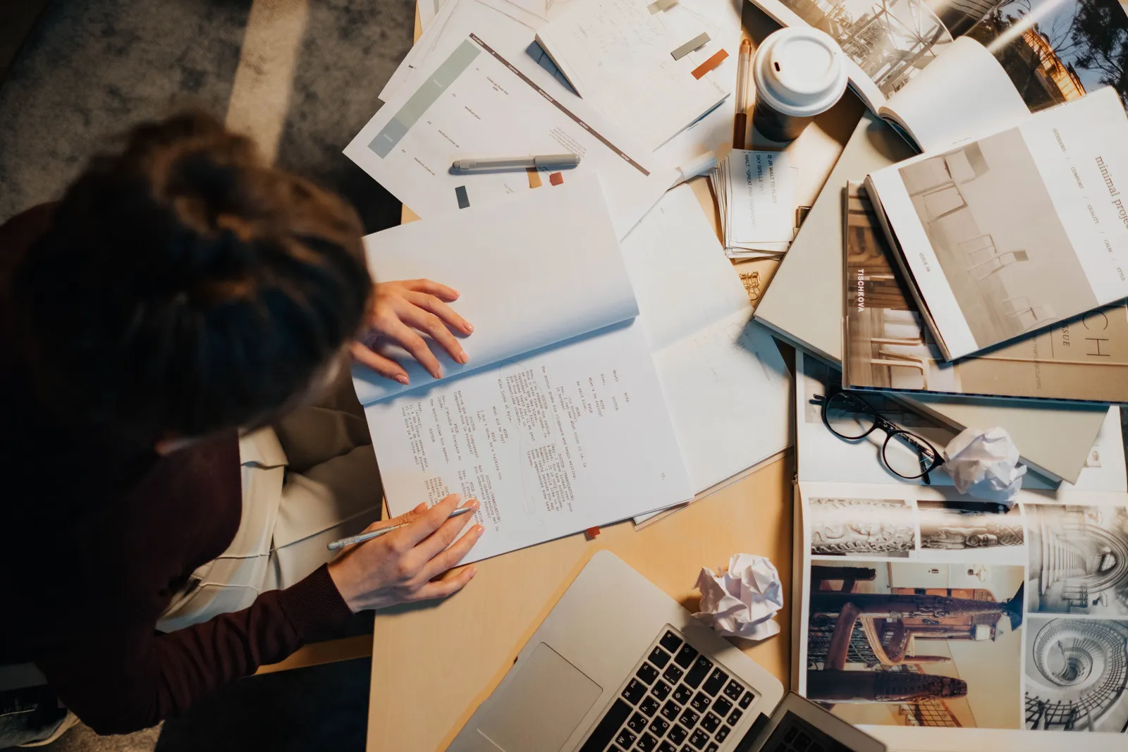 Femme assise à un bureau encombré de papiers et dossiers, vue du dessus